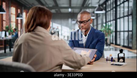 Young Woman And Man Signing House Rental Documents, Working As Legal Advisors. An African Man Holding A Key Stock Photo