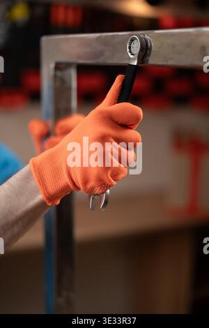 Male hands with wrench to tighten a bolt on a metal structure in workshop. Concept of craftsmanship. Stock Photo