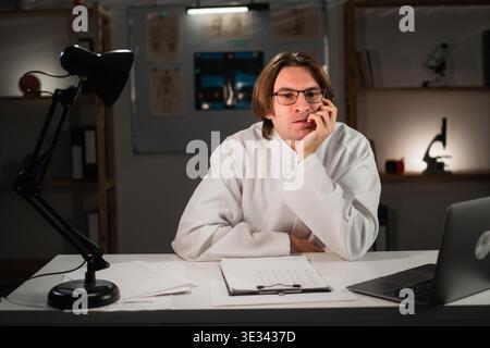worried anxious doctor biting nails working late night in his office in hospital. Copy space Stock Photo