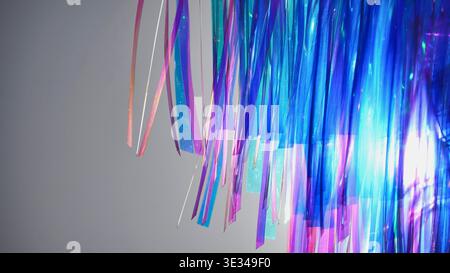Iridescent blue and purple tinsel streamers creating a vibrant abstract background Stock Photo