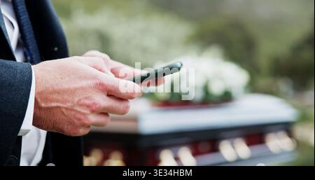 Funeral, hands and man in graveyard, smartphone for online chatting and post for memory. Family, texting and person in cemetery, cellphone or message Stock Photo