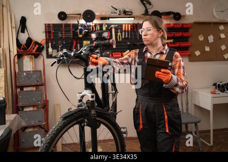 Bike repair and inspection with tablet garage or in workshop. Assessment, bicycle mechanic using digital pc. copy space Stock Photo