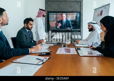 Multiethnic business team members, including arab and western professionals, attending a corporate meeting in a modern office, collaborating remotely Stock Photo