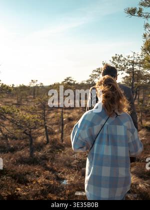 Rear view of couple in golden backlight gazing over open Kakerdaja bog Estonia in spring Stock Photo