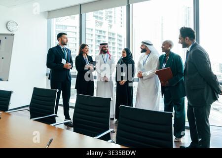 Multiethnic business people standing in a modern office boardroom overlooking city skyscrapers, discussing corporate strategies and global collaborati Stock Photo