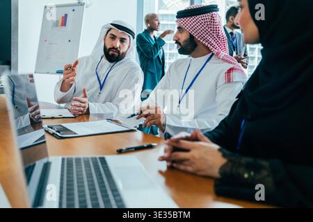 Diverse business professionals conducting a serious discussion around a boardroom table, collaborating on strategy in a modern office environment with Stock Photo