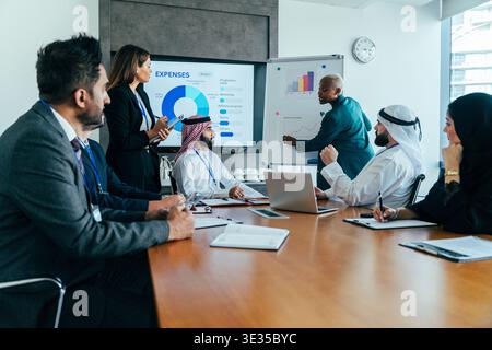 Diverse business executives attending a corporate meeting, analyzing data, presenting financial reports, and collaborating on strategies in a modern o Stock Photo