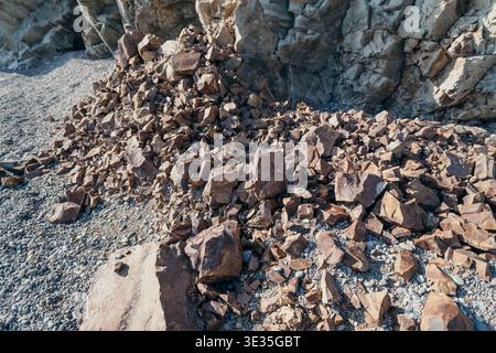 Rocks cliff stone pile of brown rubble at the base of a steep rocky cliff highlighting natural erosion and geology Stock Photo