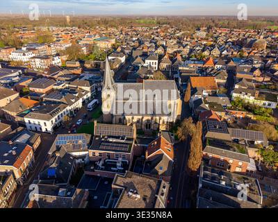 Aerial view of a European town with a historic church, traditional houses, solar‑panel rooftops and distant wind turbines, showing a blend of old arch Stock Photo