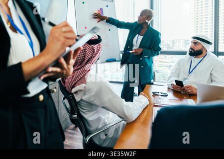 Multiethnic team in a modern office during a presentation, black manager presenting charts as colleagues take notes and discuss strategy, symbolizing Stock Photo