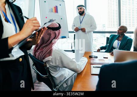 Multiethnic business team members are collaborating and focusing during a corporate meeting in a modern office, planning strategies and discussing fin Stock Photo