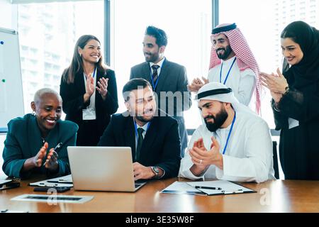 Multiethnic corporate team applauding in a modern dubai office after a successful meeting, celebrating collaboration, achievement and shared success a Stock Photo