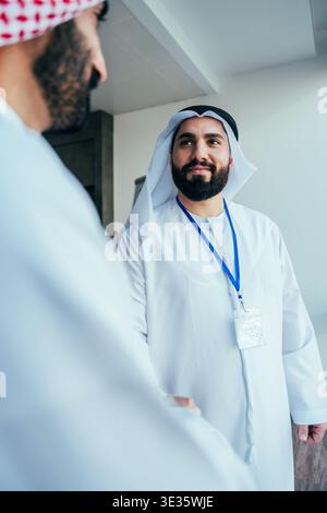 Two arab business partners in traditional clothing are shaking hands, representing business agreement, partnership, trust, and cooperation between mid Stock Photo
