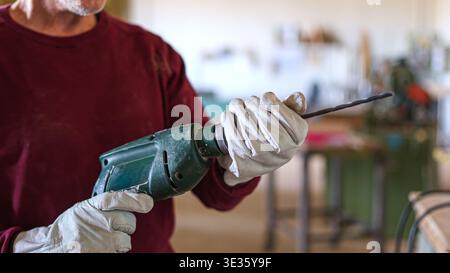 Craftsman inserting a drill bit into an electric drill Stock Photo