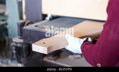 Woodworker sanding wooden board using manufacturing machinery Stock Photo