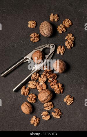 Tasty walnuts and nutcracker on black background Stock Photo
