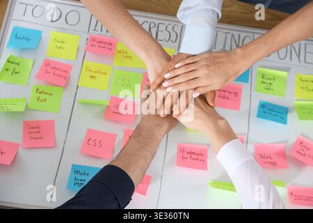 Group of people putting hands together over Kanban board in office, top view Stock Photo