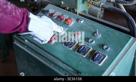 Gloved hand pressing control panel buttons in factory Stock Photo