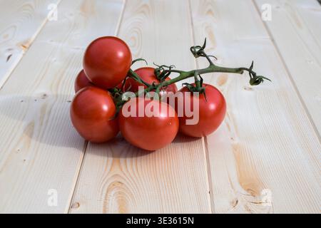 Ripe vine tomatoes displayed on a rustic wooden table, highlighting freshness, vibrant red color, and natural farm-to-table appeal. Stock Photo