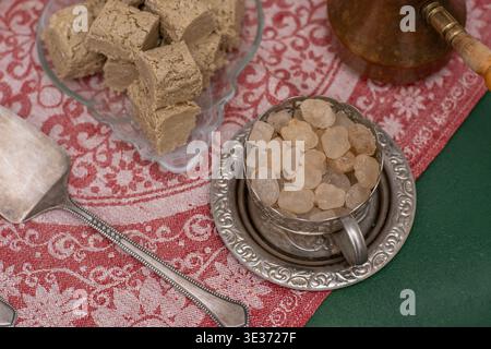 Traditional oriental rock sugar Navat in vintage metal cup on decorative tablecloth, sweet crystal candies for tea and coffee, authentic halva dessert culture. Food top view Stock Photo