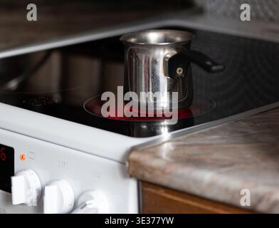Metal coffee pot on a stove in the kitchen. Stock Photo