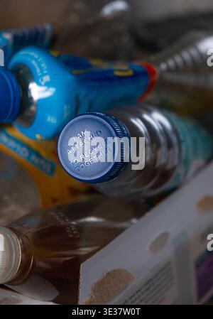 A pile of plastic bottles ready to recycle with one bottle marked on the lid with an embossed message I am attached to recycle together. Stock Photo