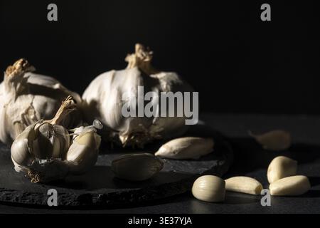 Garlic bulbs and cloves in dramatic lighting on dark background Stock Photo