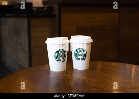 Two Starbucks coffee cups on a wooden table in a cafe. London, UK, 8 July 2023 Stock Photo