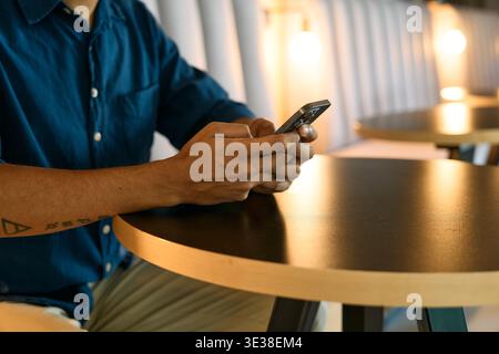 Closeup of businessman using smartphone while sitting in office lounge during evening Stock Photo