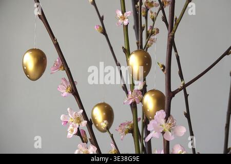 Blooming branches of a peach tree in a vase decorated with Easter eggs, spring, Germany Stock Photo