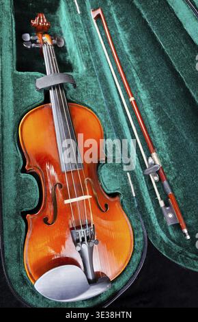 Modern small violin with bow in green velvet case close up Stock Photo