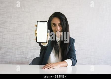 Young caucasian brunette business woman director in office excited show new app product on green blank screen text discount offer concept at work in o Stock Photo