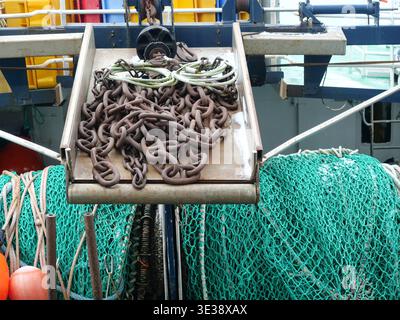 Rusty Metal Chain and Green Fishing Nets on a Working Vessel in Harbor. Maritime Industry and Fishing. Copyspace. Stock Photo