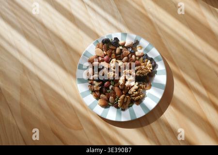 Mixed nuts and dried fruits placed on a striped plate Stock Photo