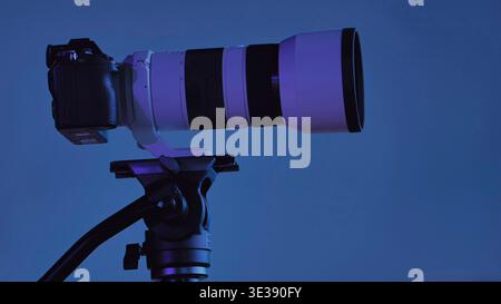 Professional camera with telephoto lens on tripod capturing imagery in studio Stock Photo