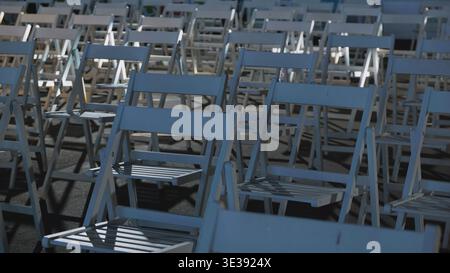 Rows of white folding chairs arranged for an outdoor assembly or event Stock Photo