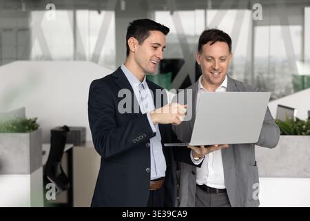 Two diverse male coworkers discussing electronic document on laptop screen Stock Photo