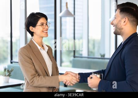 Two smiling multiethnic coworkers greeting during work break Stock Photo