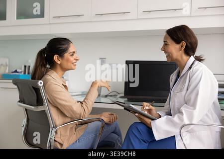 Smiling doctor consulting woman patient in clinic Stock Photo