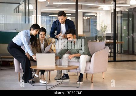 Businesspeople developing strategy for project gathered around laptop in office Stock Photo