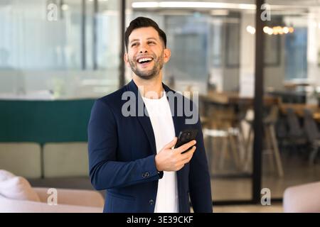 Middle Eastern businessman laughs on received message on smartphone Stock Photo