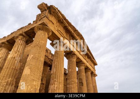 Low-angle close-up of the majestic Doric columns of the Temple of Concordia in Agrigento, Sicily. The ancient sandstone texture stands out against a c Stock Photo