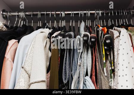 Variety of clothes on hangers in a wardrobe. Organized closet with garments in a modern minimal home interior Stock Photo