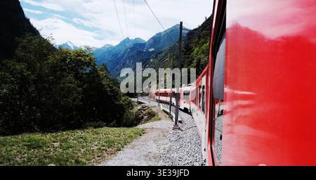 Red Train On a Path Through The Alp Mountains in Switzerland Stock Photo