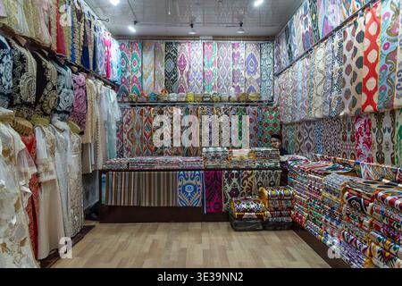 Colorful textile shop with traditional embroidered garments and stacks of patterned fabrics, showcasing vibrant craftsmanship and market culture. Stock Photo