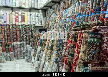Colorful rolls of patterned fabric stacked in a textile shop, showcasing rich designs and craftsmanship in a traditional market setting. Stock Photo