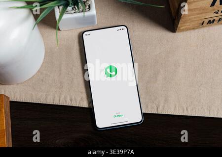 Smartphone displaying WhatsApp app on screen on desk, mobile messaging and digital communication concept. Stock Photo