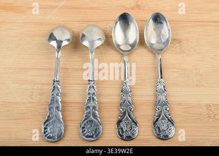 Four elegant vintage teaspoons arranged in a row on a wooden stand. Stock Photo