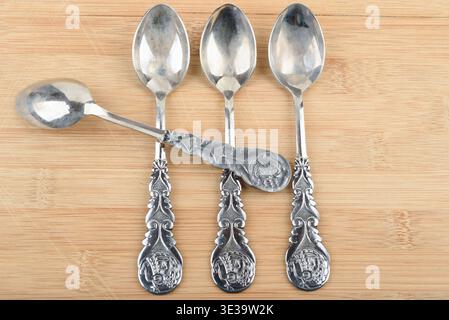Vintage silver plated teaspoons with intricate patterns on wood. Stock Photo