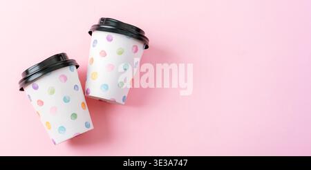 Two takeaway coffee cups with colorful polka dots on pink background. Minimal bright composition, top view. Flat lay, copy space. Stock Photo